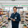 笑顔でコンビニエンスストアの店内を紹介する日本人男性の店長
