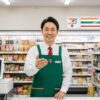 - セブンイレブンの制服を着た現役コンビニ店長（齋藤正志）が、店頭カウンターで笑顔で解説しているイメージ。