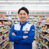 コンビニエンスストアの店内で笑顔で立つ、30代後半の日本人男性店長、齋藤正志さん。清潔感のある制服を着用し、親しみやすい表情で読者に語りかけている。