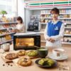 コンビニ店内で働く店長が、セブンイレブンの「お店で焼いたクッキー」を専用オーブンで温め、抹茶、紅茶など様々な種類の焼きたてクッキーとドリンクが並んだテーブルに立つ様子