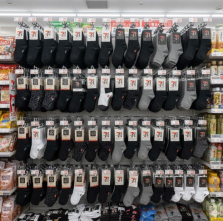 セブンイレブンの陳列棚に並べられた、様々な種類のメンズ靴下。ビジネスソックスからカジュアルソックスまで、きれいに陳列されている。