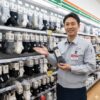 現役の日本人コンビニ店長がセブンイレブンの靴下売り場で商品を手に取り、自信を持って紹介している様子。