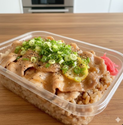 木目のテーブルに置かれた、蓋が開けられた透明な容器に入ったセブンイレブン風ねぎ塩豚カルビ弁当。レモンの輪切りと刻みネギがたっぷり乗っており、食欲をそそる。