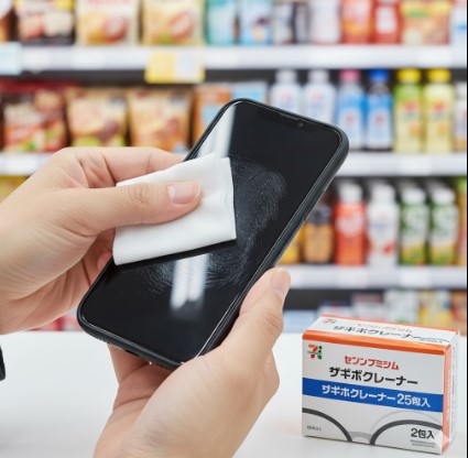 セブンイレブンのメガネクリーナーでスマートフォンの画面を拭き、指紋汚れをきれいにしている様子