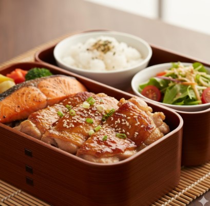 銀鮭の塩焼と鶏肉の照り焼き、ご飯、サラダが入ったバランスの良い健康的なお弁当。